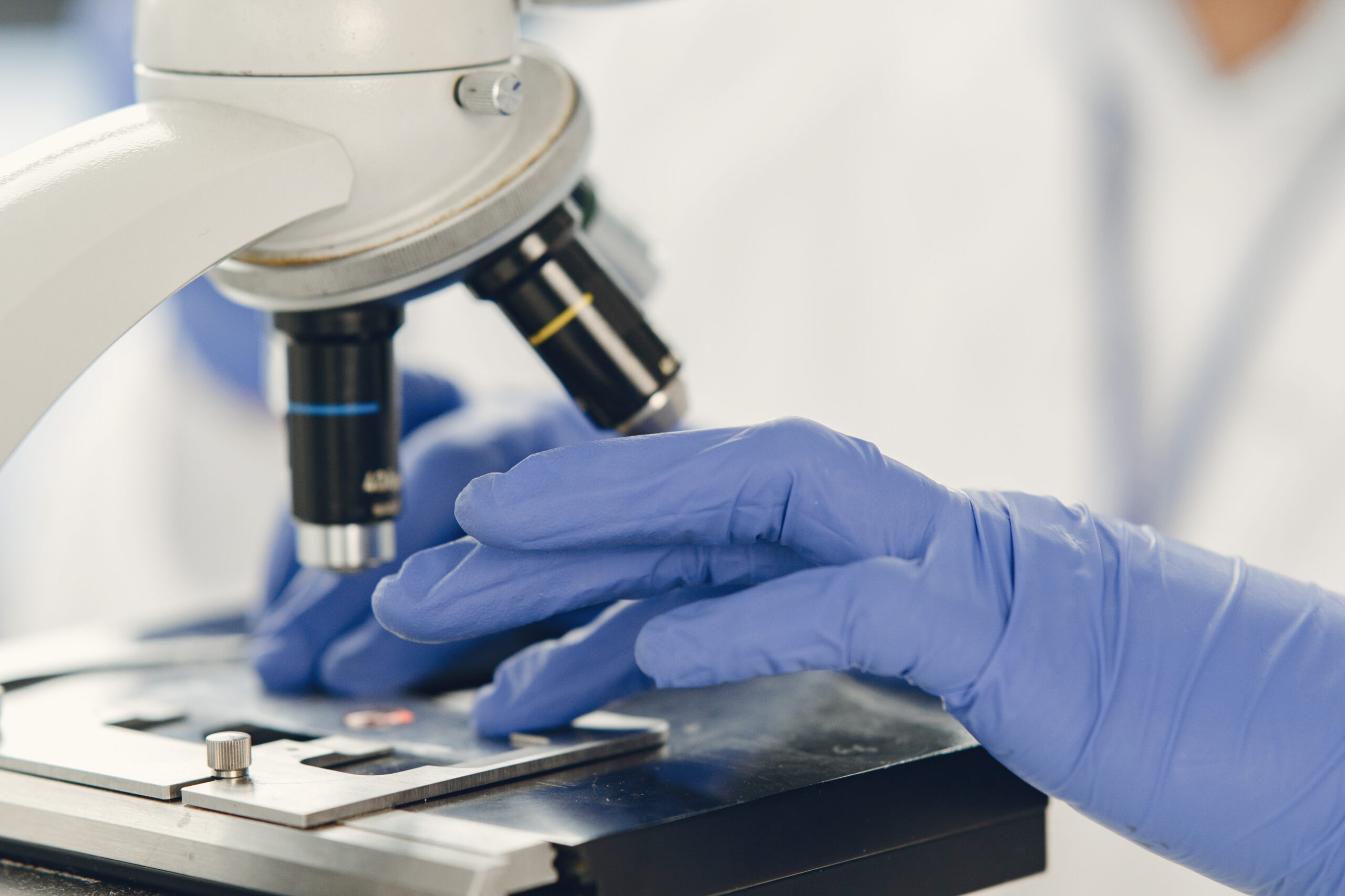professional bacteriologist putting blood sample microscope expertise covid 19 vaccine creation concept scaled